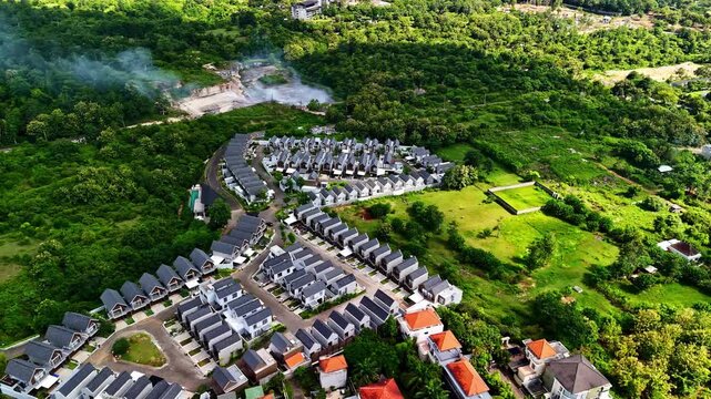 Aerial view of modern residential complex with rows of houses surrounded by lush tropical vegetation and trees in Bali, Indonesia.