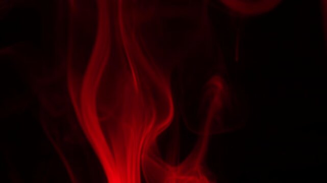 Red smoke rises on a dark background, creating an abstract texture and atmospheric effect. This visual provides a versatile design element for overlays and graphic compositions. The fluid motion and