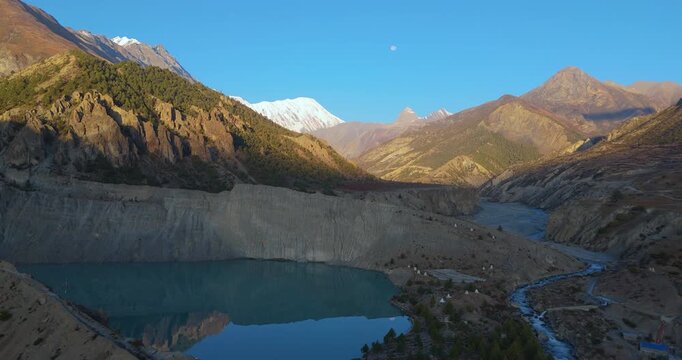 Annapurna Circuit, Manang region, Nepal, aerial shot of Gangapurna Lake alongside Marsyangdi River with snow capped Tilicho Peak in morning sunlight.