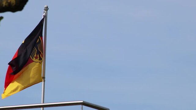 Official German flag waving in the wind and fluttering German flag as sign for Germany and the German identity in Berlin as center of Europe. The tricolor in black, red and gold represents Germany.