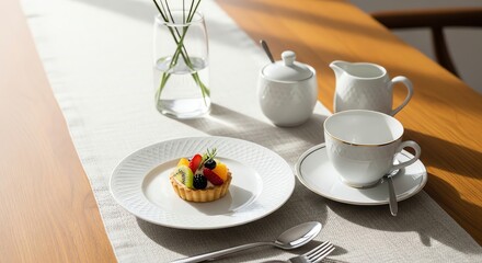 Fototapeta premium A colorful fruit tart on a white porcelain plate, part of an elegant tea service on a sunlit table.