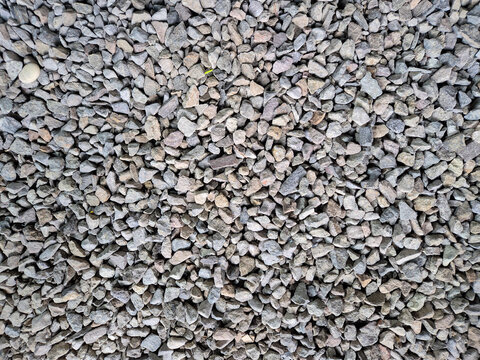 Top view of crushed gray stones forming a rough gravel texture, ideal as a natural construction background or seamless rock pattern