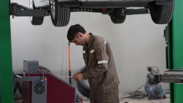 Car mechanic in garage checking vehicle on lift during repair workshop inspection with tools and diagnostic service in auto bay