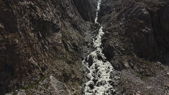 Close-up of a rapid mountain waterfall flowing through dark rocks in Ala Archa National Park, Kyrgyzstan