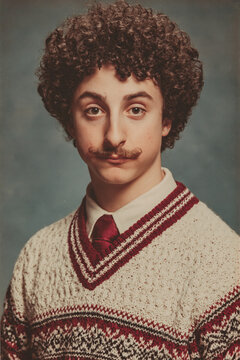 people of ai, yearbook photography of a person with short tight brown curls, mustached, wearing cream patterned sweater, 1970s portrait gold, photorealistic