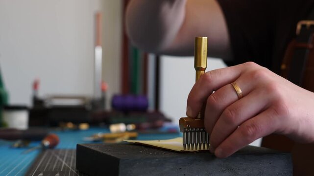Artisan hands using a heavy mallet and a brass stitching punch to make holes in leather. Close-up of Punching Holes in Leather 4k video