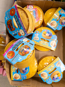 Varna. Bulgaria. 29.07.2026 Dumpling toy antistress products in yellow round containers with colorful branded packaging are displayed inside a cardboard box in a retail store setting