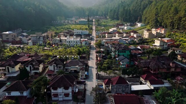 Aerial view of Wisata Bukit Sekipan Tawangmangu showing residential houses, lush greenery, and a straight road in the highlands in Kecamatan Tawangmangu, Jawa Tengah, Indonesia.