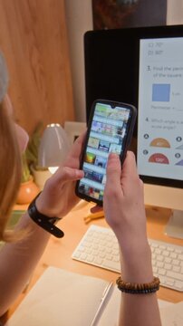 Vertical video of teenage student scrolling on smartphone while neglecting online school lesson on computer screen. Clip is ideal for e-learning ads and digital distraction concepts