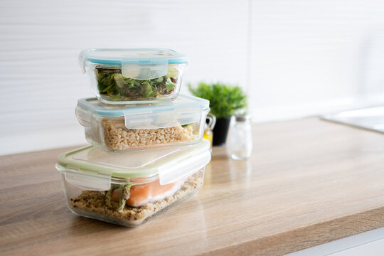 Healthy meal prep containers stacked on kitchen table. Copy space