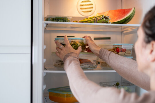Person organizing reusable glass meal prep containers.