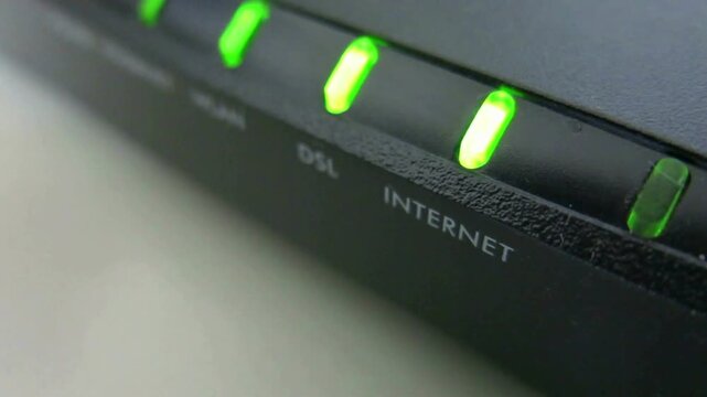 Close up of blinking green indicator lights on a black broadband internet router.