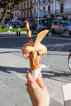 Gelato artigianale di una gelateria servito su un cono croccante e mantenuto in mano da un cliente