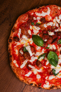 Pizza tradizionale napoletana con sugo di pomodoro, mozzarella, melanzane, polpette fritte e basilico fresco appena sfornata e servita in pizzeria