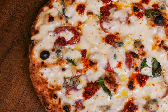 Pizza tradizionale napoletana a ruota di carro con mozzarella, salame piccante, nduja calabrese e basilico servita in una pizzeria