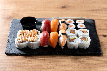 Assorted sushi platter with salmon, tuna, shrimp nigiri and sushi rolls on wooden table © chandlervid85