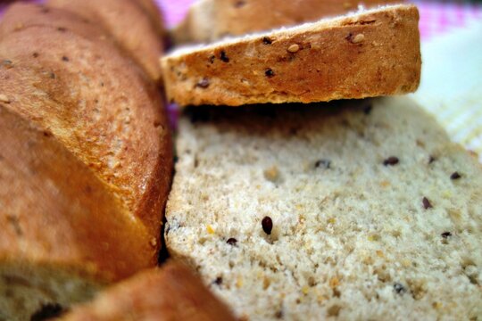 Close up view of a sliced loaf of artisan grain bread showing a textured crumb and crust with visible seeds for a nutritious homemade food concept