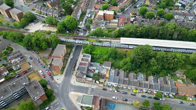 Aerial view of Peckham railway station with trains at the platform surrounded by residential houses and lush green trees in London, England, United Kingdom.