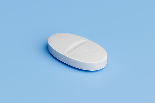 White oval tablet pill on light blue background