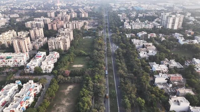 Aerial view of a road lined with trees and residential apartment buildings in Greater Noida, Uttar Pradesh, India.