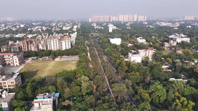 Aerial view of the Omicron I neighborhood featuring residential apartment complexes, lush green tree-lined streets, and urban infrastructure in Greater Noida, Uttar Pradesh, India.