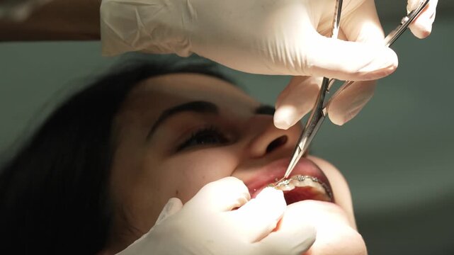 Orthodontist placing dental braces on patient's teeth