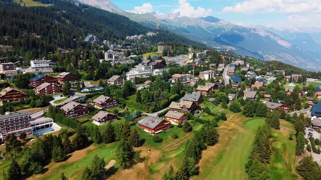 Aerial view of Guarda Golf Hotel and surrounding alpine resort town with chalets and golf course in Crans-Montana, Valais, Switzerland.