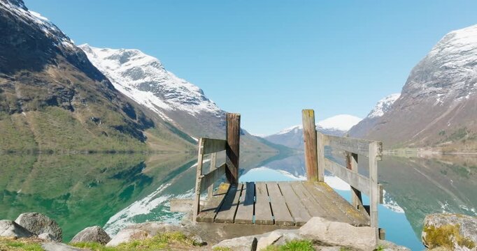 Drone Glides Past Wooden Pier and Mountain Reflections at Lovatnet