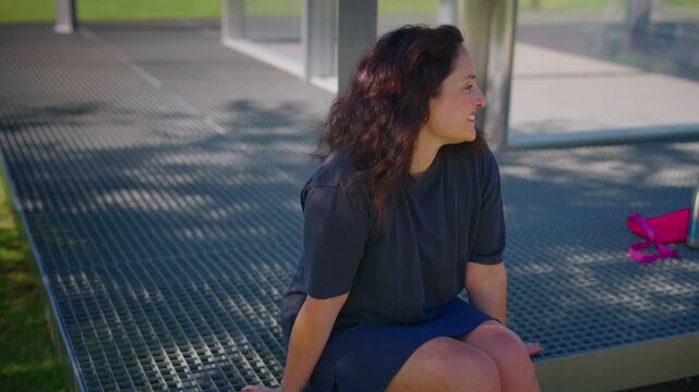 A Joyful Moment in Nature: A Woman Smiling Brightly While Sitting on a Bench Surrounded by Greenery and Sunlight, Radiating Happiness and Positivity
