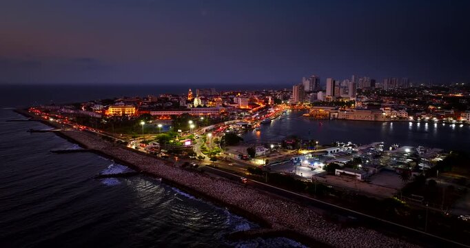Car traffic on coastal road and illuminated buildings at dusk in Cartagena, Colombia. Aerial view, cityscape, copy space