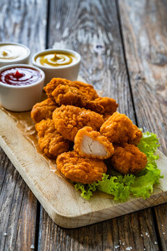 Air fryer breaded chicken nuggets with mayonnaise, ketchup and mustard on wooden table
