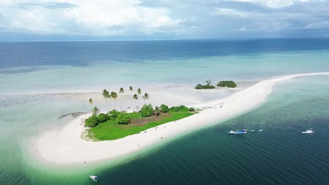 Aerial view of a tropical island also called with Spongebob Island with white sand beaches, lush palm trees, and small boats in the turquoise water of Berau, East Borneo, Indonesia.