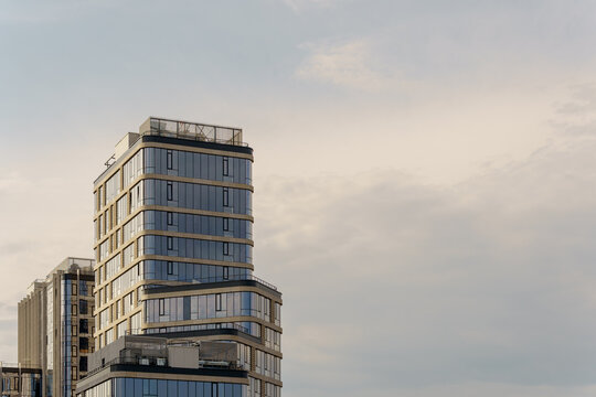 Glass skyscraper corner fragment next to vast cloudy copespace sky. Modern apartment tower top in minimal composition.