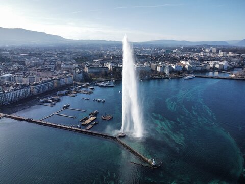 Aerial view of the iconic Jet d'Eau fountain spraying water into Lake Geneva with the city skyline and mountains in the background in Geneva, Geneva, Switzerland.