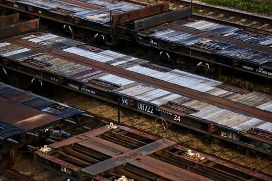Aerial view of freight flatbed railway wagons with wooden deck parked in a train depot, rusty industrial rail cars