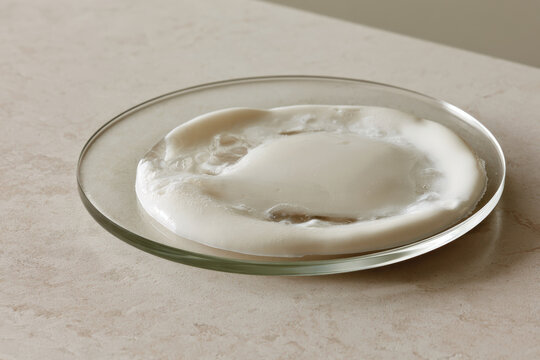 A translucent white shape spreads across a glass surface, accentuated by its fluid form, inviting exploration of texture and light, fostering an atmosphere of tranquility and elegance.