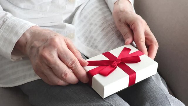 赤いリボンのプレゼントを受け取る高齢女性の手元／敬老の日