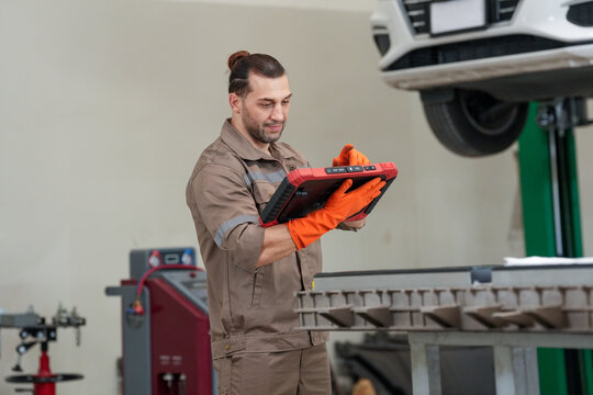 Mechanic car tablet garage repair inspection glove lift, male mechanic using tablet during car inspection in garage