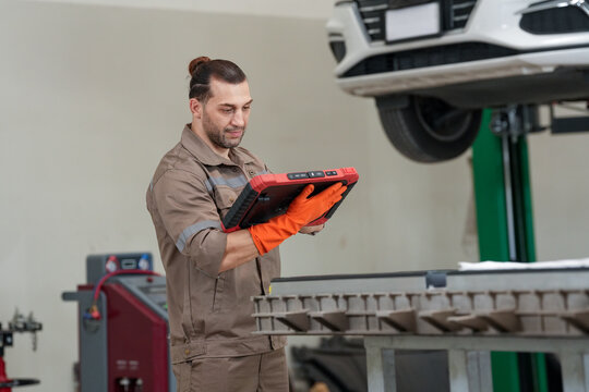 Car mechanic tablet garage inspection vehicle repair lift male technician using tablet during vehicle inspection garage with raised car