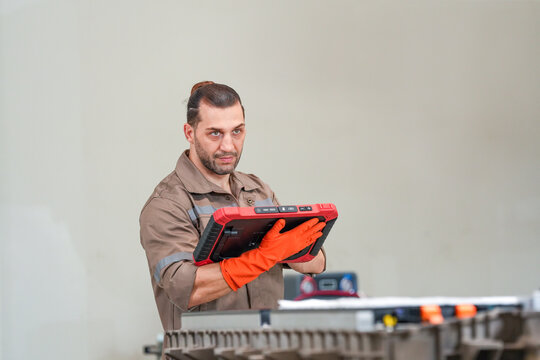 Technician tablet glove car repair diagnostic workshop male worker with focused expression using digital tool near vehicle part