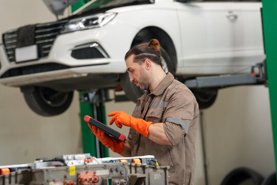 Mechanic car garage tablet glove vehicle repair service male technician using digital tablet beside lifted automobile