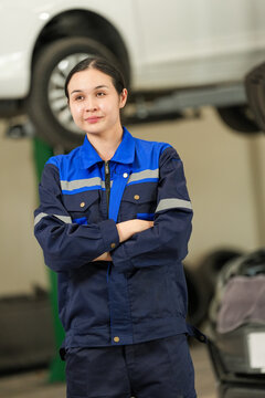 Mechanic woman car garage uniform arms crossed vehicle lift confident automotive repair workshop service