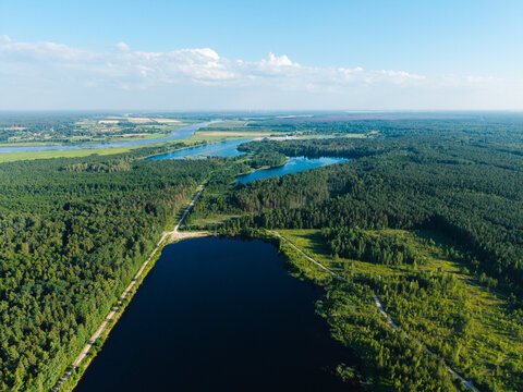 Aerial view of Kalnciems Dolomite Quarry featuring deep water-filled pits surrounded by dense forests and industrial peat extraction landscapes in Valgunde Parish, Jelgava Municipality, Latvia.
