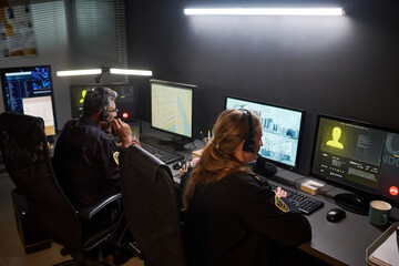 Diverse security officers monitoring surveillance screens and coordinating response in control room. Ideal for public safety, emergency dispatch, crime prevention campaigns