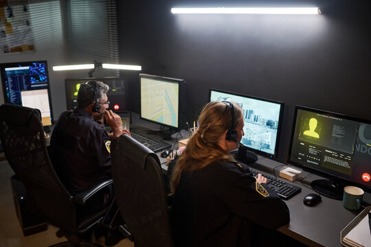 Diverse security officers monitoring surveillance screens and coordinating response in control room. Ideal for public safety, emergency dispatch, crime prevention campaigns