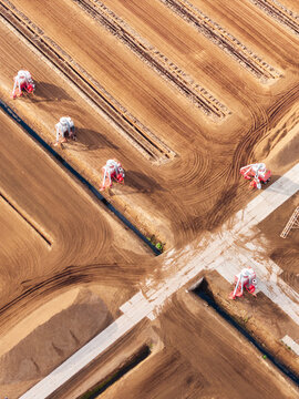 Aerial view of peat extraction machinery operating in the Kaigu Bog Nature Reserve with geometric drainage channels and brown soil patterns in Kaigu ciems, Jelgavas novads, Latvia.
