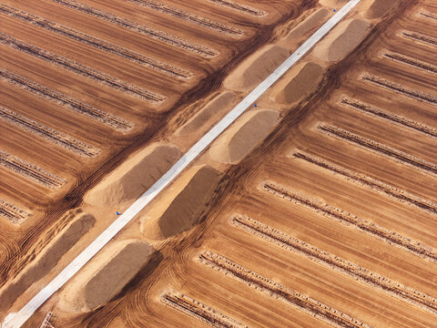 Aerial view of the peat extraction fields at Kaigu Bog Nature Reserve with long parallel rows of harvested peat and a central access road in Kaigu ciems, Jelgavas novads, Latvia.