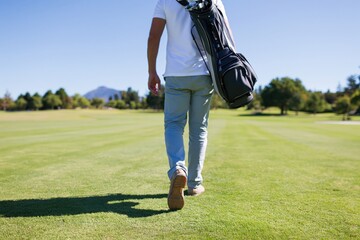 Obraz premium The Golfer Carrying Golf Bag On Sunlit Open Golf Course