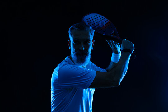 Padel tennis player with racket. Man athlete with paddle racket on court with neon colors. Sport concept.
