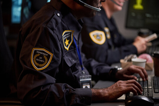 Close up of security officers monitoring screens and typing at control center, managing surveillance operations. Ideal for cybersecurity, public safety, risk management campaigns